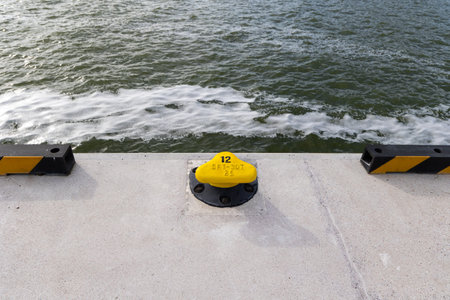 Yellow mooring hook on the concrete quay. Safety of boats moored to the waterfront. Photo taken on a...