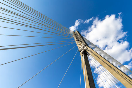 Fixing the ropes in the concrete pylon of the rope bridge. View of the bridge structures against the blue skyの写真素材