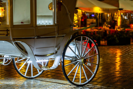 The wheel of a white carriage carrying tourists around the Old Town Square in Cracow. Night shot taken with natural city lighting.の写真素材