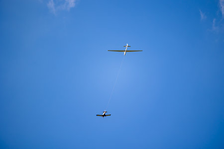 White glider plane being pulled by other small airplane towards the blue sky. Glider pulling on a sunny day.の写真素材