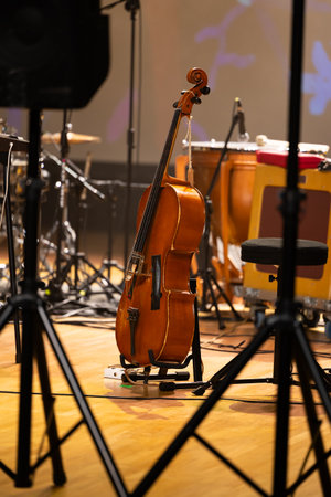 Cello on a stand placed on the stage. Photo taken with artificial light in the concert hall during a break in the concertの写真素材