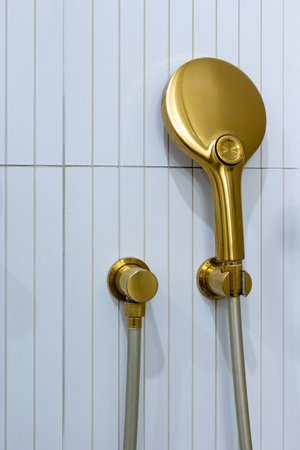 Bronze, braas bathroom handshower in a bathroom finished with white tiles. Minimalist bathroom finish. Photographed in natural light.の写真素材