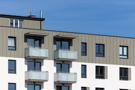 White and beige facade of a newly built apartment block. Clear blue sky above the building. Photo...