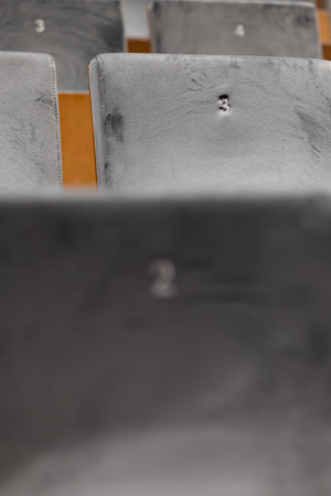 Rows of empty seats in a cinema hall, front side of the seats with numbers. Close-up with shallow...