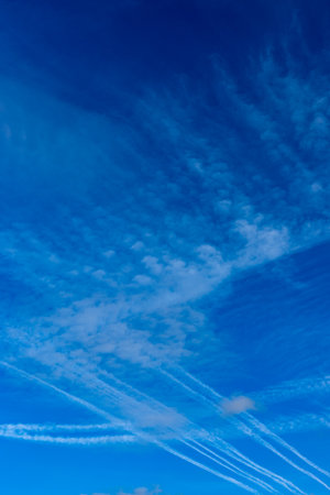 Condensation trails against a blue sky. Photo taken on a sunny dayの写真素材