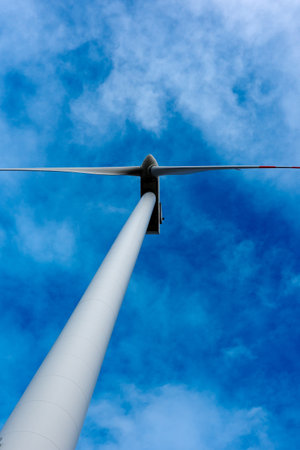 White wind turbine rotor against a blue sky background. Electric generator photographed from below