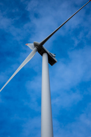 White wind turbine rotor against a blue sky background. Electric generator photographed from below