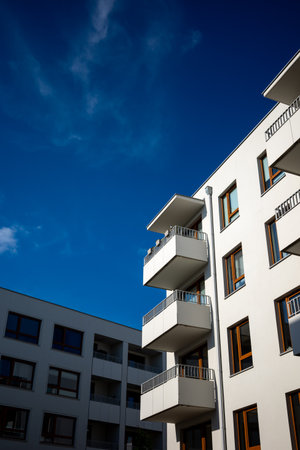 The facades of white apartment buildings against a blue sky. Modern multi-family housing.