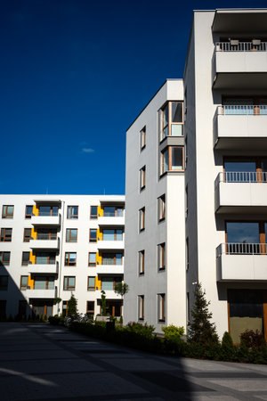 The facades of white apartment buildings against a blue sky. Modern multi-family housing.