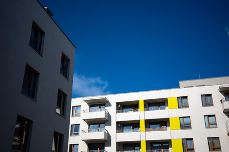 The facades of white apartment buildings against a blue sky. Modern multi-family housing.