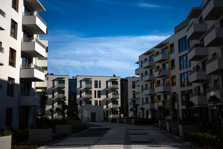 The facades of white apartment buildings against a blue sky. Modern multi-family housing.