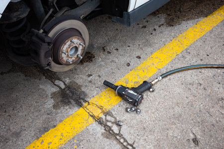A pneumatic wrench used to change a flat tire on a passenger car. The hub and brake discs are visible after removing the wheel.の写真素材