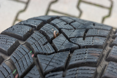 A wire sticking out of the tread of a flat tire. Tire punctures caused by road debris.