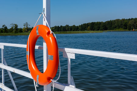 Orange swimming rescue wheel hung on the rails of the white jetty. Safety equipment on the water...