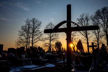 Silhouette of a cemetery cross against the orange sunset sky. Photo taken in autumn, just before evening.の写真素材