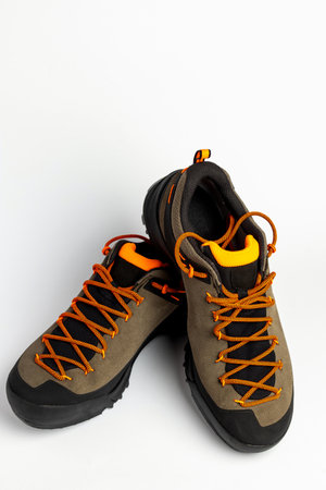 Hiking boots with colorful orange laces on a white background. Photo taken under artificial...