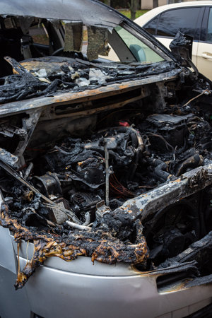 Burnt motor compartment of passenger car standing on the city street. Vehicle with interior largely...