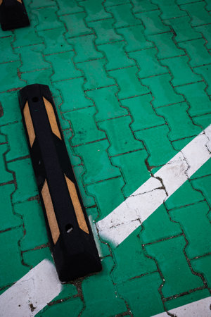 Rubber parking barriers in the green-paved parking lot.
