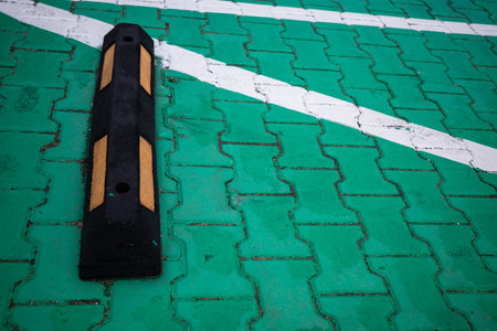 Rubber parking barriers in the green-paved parking lot. A space reserved for electric cars.