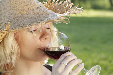 young woman with sun hat drinking red wine
