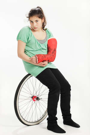 Girl with wheel and plaster cast. Studio shot against a white background.の写真素材