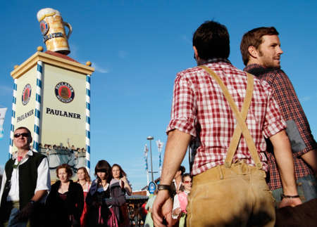 Munich, Germany - October 03, 2010: In the foreground two men in bavarian costume at the traditional Oktoberfest at the Theresienwiese, in the background a tower of the Bavarian beer brand Paulaner for advertising.のeditorial素材