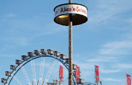 Munich, Germany - October 03, 2010: Advertising for the traditional Oktoberfest tavern Wies'n SchÃ¤nke, Ferris Wheel against the blue sky.のeditorial素材