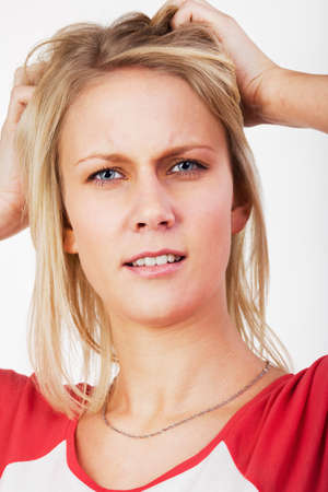Portrait of young blonde woman with hands in her hair looking dubiously.の写真素材