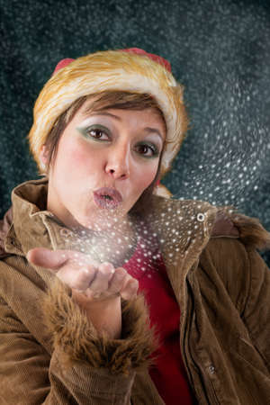 Pretty female Santa Claus as christmas fairy blowing a kiss out of snow and stars  Sensual Studio portrait against a dark green backgroundの写真素材