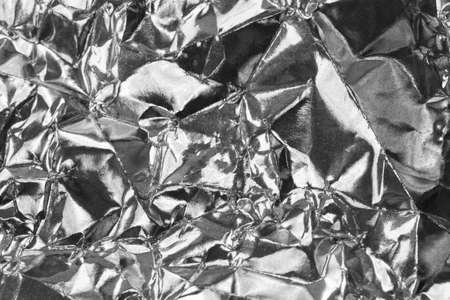 Detail close up of wrinkled metallic paper as a monochrome structured background image in black and white with focus at the centerの写真素材