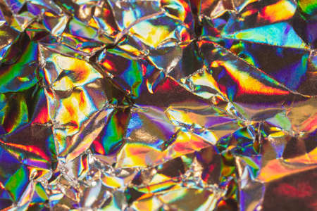Detail close up of strongly wrinkled metallic paper as a colorful fantasy background image in rainbow colors with focus at the centerの写真素材