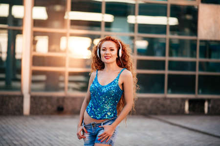 Positive redhead young female with mobile phone in subway train. Moscow metro.