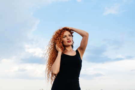 Beautiful redhead girl on the sky backgroundの写真素材