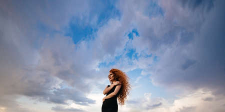 Redhead girl at spring blue sky background.の写真素材
