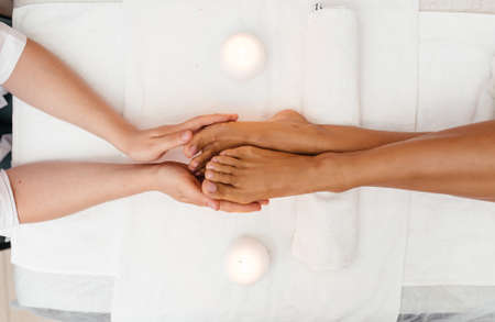 Ayurveda foot massage with oil on the wooden table in traditional style made by asian women. Top view.の写真素材