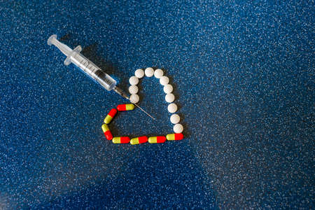 Medical pills and tablets spilling out of a drug bottle with syringe.の写真素材