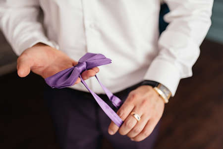 A man holds a bow tie in his hands.の写真素材