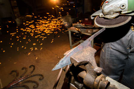 Blacksmith, knife sharpening, sparks, metal. Forging molten metal. Making knives.forge workshopの写真素材