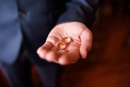 On a man's palm are two wedding rings. The groom holds the rings. wedding tradition. Gold rings lie on a man's palmの写真素材