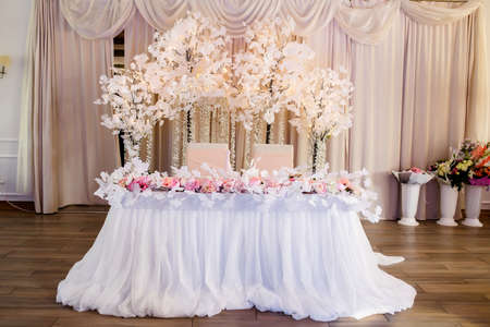 Stylish table setting with dried flowers. Plate with vintage golden fork and knife, candles, dusty blue napkins on wooden table. winter wedding decorationの写真素材