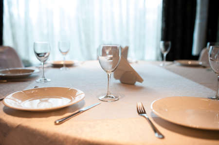 Empty plate, glasses and silverware set on wooden tableの写真素材