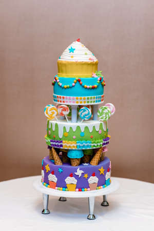 Beautiful multi-colored children's cake from several layers decorated with sweetsの写真素材