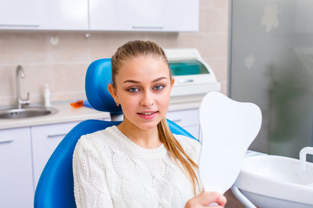 The girl smiles in dentistry. patient dentist racing model at the Dental Clinic. White well-groomed teeth after taking a doctor. Tooth whitening and tooth enamel.の写真素材
