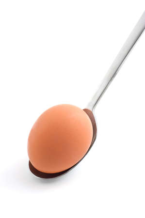 Fresh brown egg in stainless steel spoon isolated on white background in vertical formatの写真素材