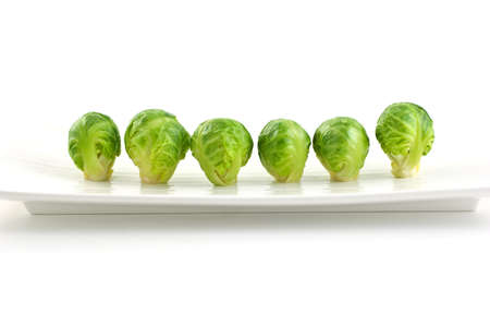 Row of brussel sprouts on long white plate isolated on white backgroundの写真素材