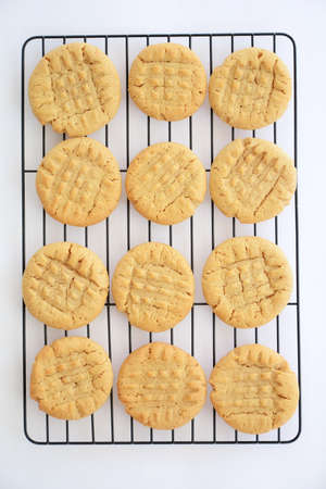 Fresh baked peanut butter cookies cooling on black rack shot from overhead in natural light