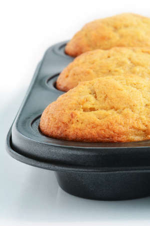 Fresh baked home made banana muffins in muffin tin.  Vertical format with selective focus on front...