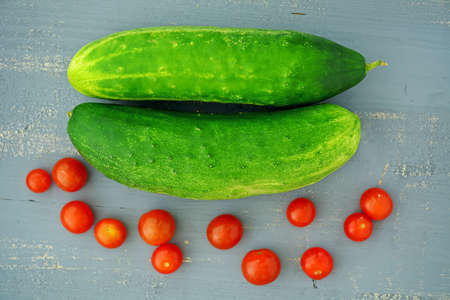 Cucumbers and cherry tomatoes picked fresh from home garden on rustic background in flat layの写真素材