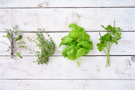 Fresh organic picked herbs on white weathered boards background shot from above. Healthy eating...