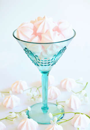 Delicate pink meringue candy kisses in aqua wine glass in vertical format. Selective focus on top meringue.の写真素材